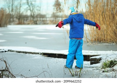 A Child In Danger On Thin Ice In Winter. The Boy Is Ice Skating On A Frozen Lake.