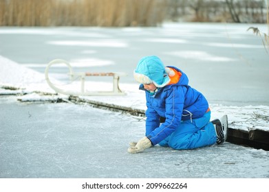 A Child In Danger On Thin Ice In Winter. The Boy Is Ice Skating On A Frozen Lake.