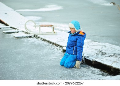 A Child In Danger On Thin Ice In Winter. The Boy Is Ice Skating On A Frozen Lake.