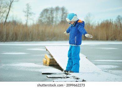 A Child In Danger On Thin Ice In Winter. The Boy Is Ice Skating On A Frozen Lake.