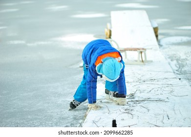 A Child In Danger On Thin Ice In Winter. The Boy Is Ice Skating On A Frozen Lake.