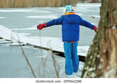 A Child In Danger On Thin Ice In Winter. The Boy Is Ice Skating On A Frozen Lake.