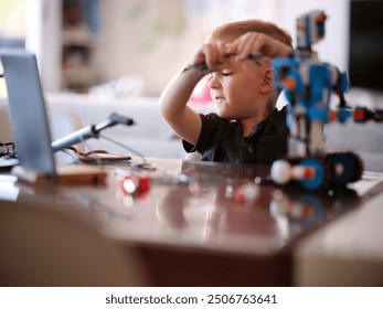 A child is deeply engaged in assembling a robot with a laptop nearby, capturing a moment of focused curiosity and hands-on learning in a modern home setting.