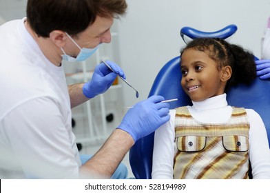 A Child And A Dentist Look At Each Other, Talking And Smiling