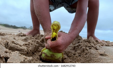 
Child Digging Hole At The Beach Playing With Shovel