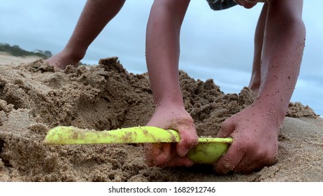 
Child Digging Hole At The Beach Playing With Shovel