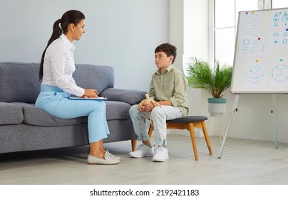 Child Discussing His Problems With A Therapist. Woman Who Works As A Psychotherapist Or School Psychologist Sitting On The Sofa And Talking To A Little School Boy. Children's Psychology Concept