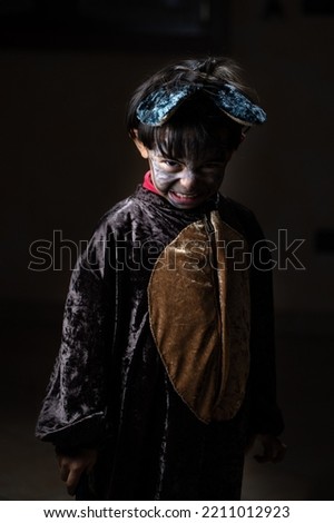 Child disguised as a werewolf during Halloween. Threatening face while showing fauci and artagli, on dark background