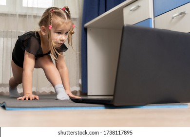 The Child Does Gymnastics On A Gymnastic Rug At Home In Front Of A Computer. Distance Learning Sports