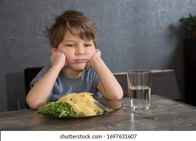 El niño no quiere comer. El niño come espaguetis. Pobre apetito. Dieta sana. Se niega a comer. Un niño disgustado a la hora del almuerzo.