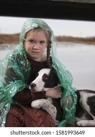 A Child And A Dog In A Flood Disaster Area. The Girl Was Crying, Soaked In The Rain