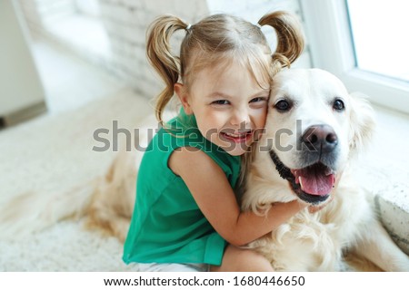 A child with a dog. Little girl with labrador retriever at home.