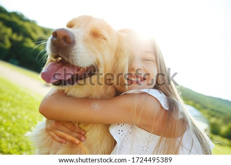 A child with a dog in nature. girl playing with a dog on green grass at sunset time.