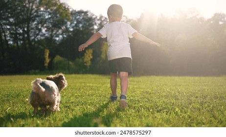 Child and dog is running on the grass. Happy pet fun concept. A dog is running around in a park with kids. A kid and a child are running on the grass near lifestyle a dog. - Powered by Shutterstock