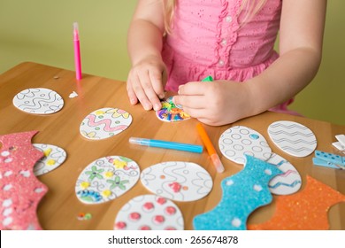 Child Doing Easter Activities And Crafts With Bunny Stickers, Easter Egg Shapes, Pencils And Markers.