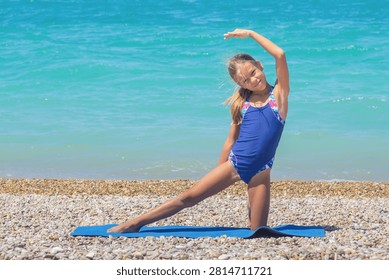 Child doing gate pose on pebble beach over seaside