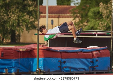 a child doing height jump during a school olympics jumping over the bar - Powered by Shutterstock