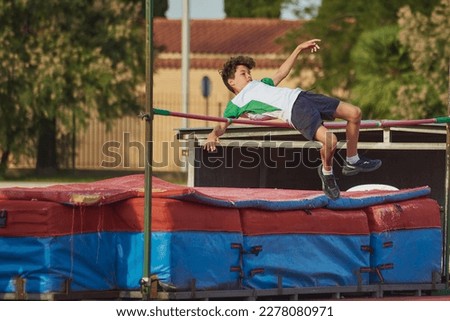 a child doing height jump during a school olympics jumping over the bar