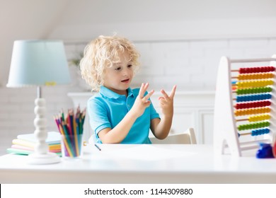 Child Doing Homework At Home. Little Boy With Wooden Colorful Abacus Doing Math Exercise Learning Addition And Counting. Kids Study And Learn. Preschooler Kid Writing And Reading. Back To School.