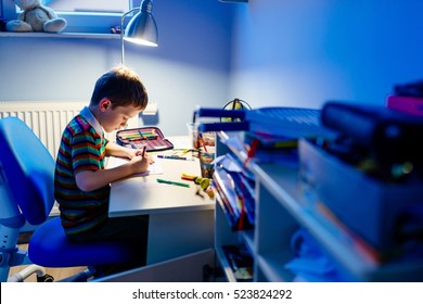 Child Is Doing Homework In The Light Of The Lamp In The Evening