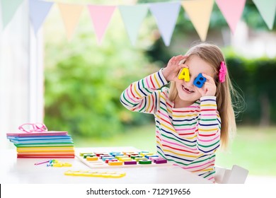 Child Doing Homework For School At White Desk. Wooden Educational Abc Toy Puzzle For Kids. Happy Back To School Student. Kid Learning Alphabet Letters. Little Girl With School Supplies And Books.