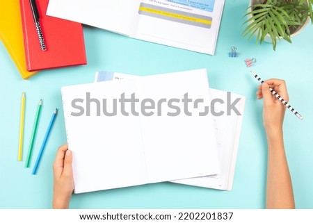 Child doing homework. Top view to desk with open blank notebook, books, colored overlay strips for Dyslexia students, school supplies. Education, learning disability, reading difficulties, dyslexia