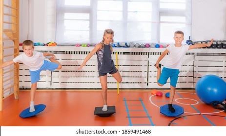 Child doing uni-pedal stance on a balancing disc during physical activity training, balance and coordination improvement