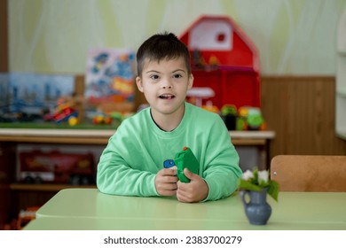A child with Down syndrome plays in kindergarten - Shutterstock ID 2383700279