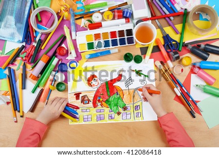 child drawing boy fly with air screw on his back, top view hands with pencil painting picture on paper, artwork workplace