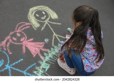 Child Drawing Family With Chalk On Asphalt