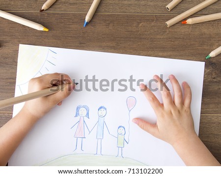 Child drawing happy family on paper. Top View