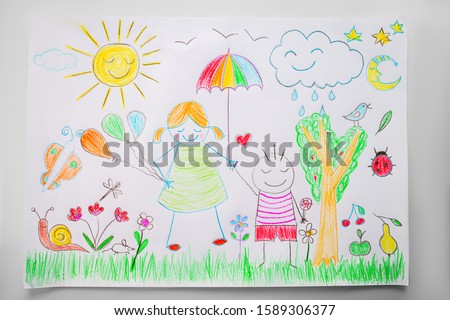 Child drawing a happy family in a park with color pencils.