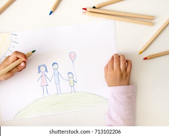 Child drawing her family on paper - Shutterstock ID 713102206