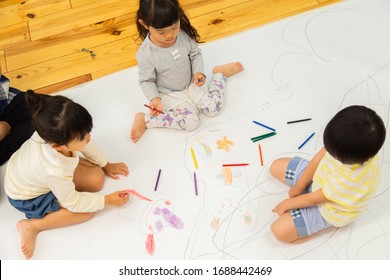 A Child Drawing On A Large Drawing Paper