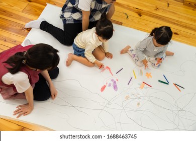 A Child Drawing On A Large Drawing Paper