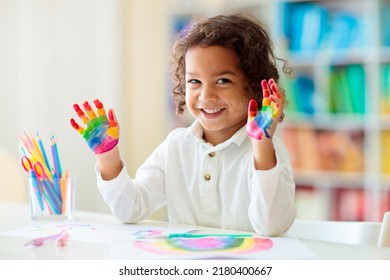 Child drawing rainbow. Paint on hands. Remote learning and online school art homework from home. Arts and crafts for kids. Little boy drawing bright picture. Creative kid playing and studying.