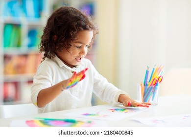 Child drawing rainbow. Paint on hands. Remote learning and online school art homework from home. Arts and crafts for kids. Little boy drawing bright picture. Creative kid playing and studying. - Powered by Shutterstock