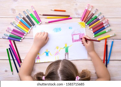 A child draws a birthday card with his family. The drawing was made by a child using colored markers and pencils. Happy family. Children's drawing. View from above.