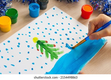 A child draws Christmas tree  Ideas for drawing and bright colors  Drawing children white background  A little girl draws and paint   brushes  The concept children's development