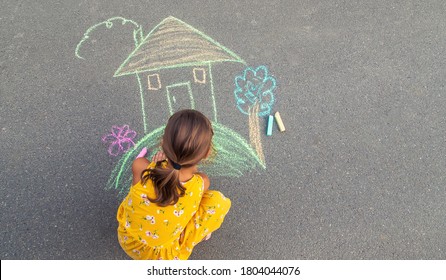 The Child Draws A House On The Asphalt. Selective Focus. Kid.