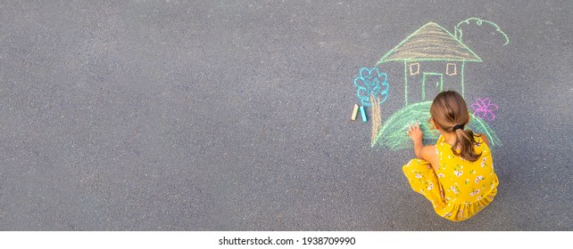 The child draws a house on the asphalt. Selective focus. kid. - Shutterstock ID 1938709990
