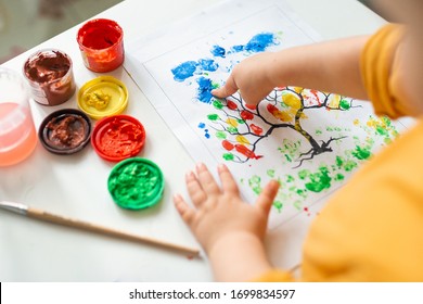 A child draws leafs tree  Ideas for drawing and finger paints  Finger painting for kids white background  Little girl painting by finger hand paint color  Children development concept  