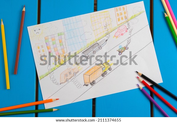 Child draws a pencil drawing of the city, cars and\
air pollution. Top view.