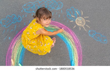 A child draws a rainbow on the asphalt. Selective focus. kid. - Powered by Shutterstock