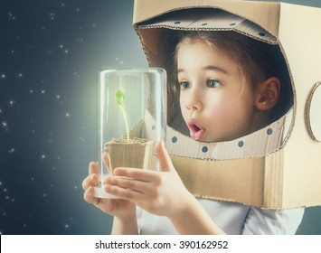 Child is dressed in an astronaut costume. Child sees a sprout in a glass case. The concept of environmental protection.