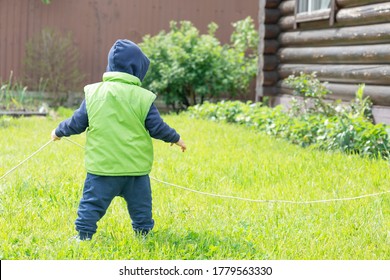 Ein Kind, das in einer Weste gekleidet ist, dehnt einen elektrischen Draht auf grünem Hintergrund aus