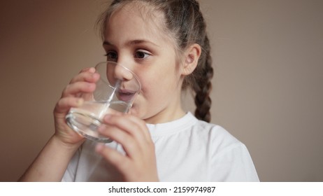 Child Drinking Water. Little Girl Lifestyle In The Kitchen Drinks Water From A Glass Cup. Problem Of Shortage Of Drinking Water In The World Concept. Kid Drinking Clean Water From A Glass