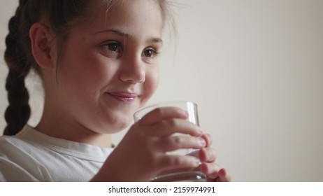 Child Drinking Water. Little Girl In The Kitchen Drinks Water From A Glass Cup. Lifestyle Problem Of Shortage Of Drinking Water In The World Concept. Kid Drinking Clean Water From A Glass