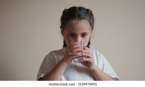 Child Drinking Water. Little Girl In The Kitchen Drinks Water From A Glass Cup. Problem Of Shortage Of Drinking Water In The World Concept. Kid Drinking Clean Lifestyle Water From A Glass