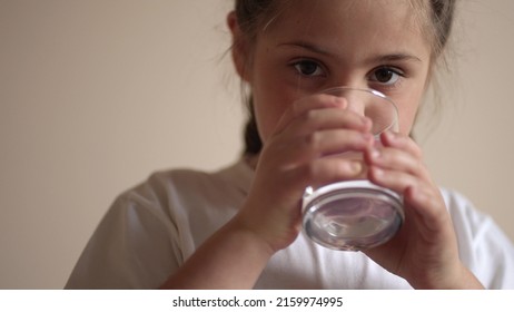 Child Drinking Water. Little Girl In The Kitchen Drinks Water From A Glass Cup. Problem Of Shortage Of Drinking Water In The World Concept. Kid Lifestyle Drinking Clean Water From A Glass